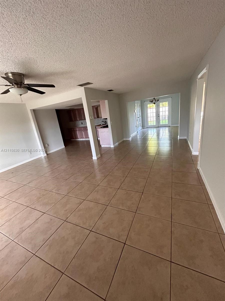 Open-concept floor plan featuring ceramic tile flooring, a multi-blade ceiling fan, recessed lighting, and double glass-paned doors