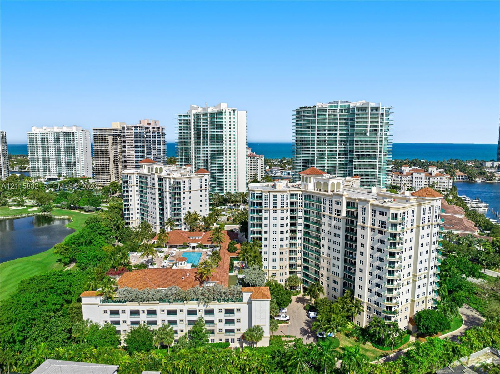 High-rise residential exterior featuring terracotta tile roofing, multi-story balconies, outdoor swimming pool, and manicured grounds, set against a coastal skyline