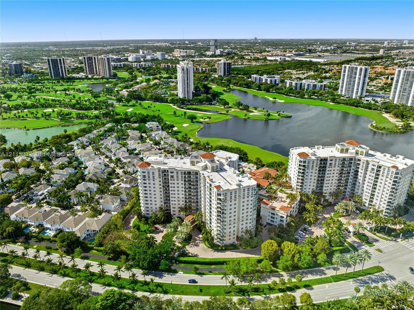 High-rise residential building featuring a multi-story exterior, tiled roof, surrounding landscaped grounds, and proximity to a lake and golf course