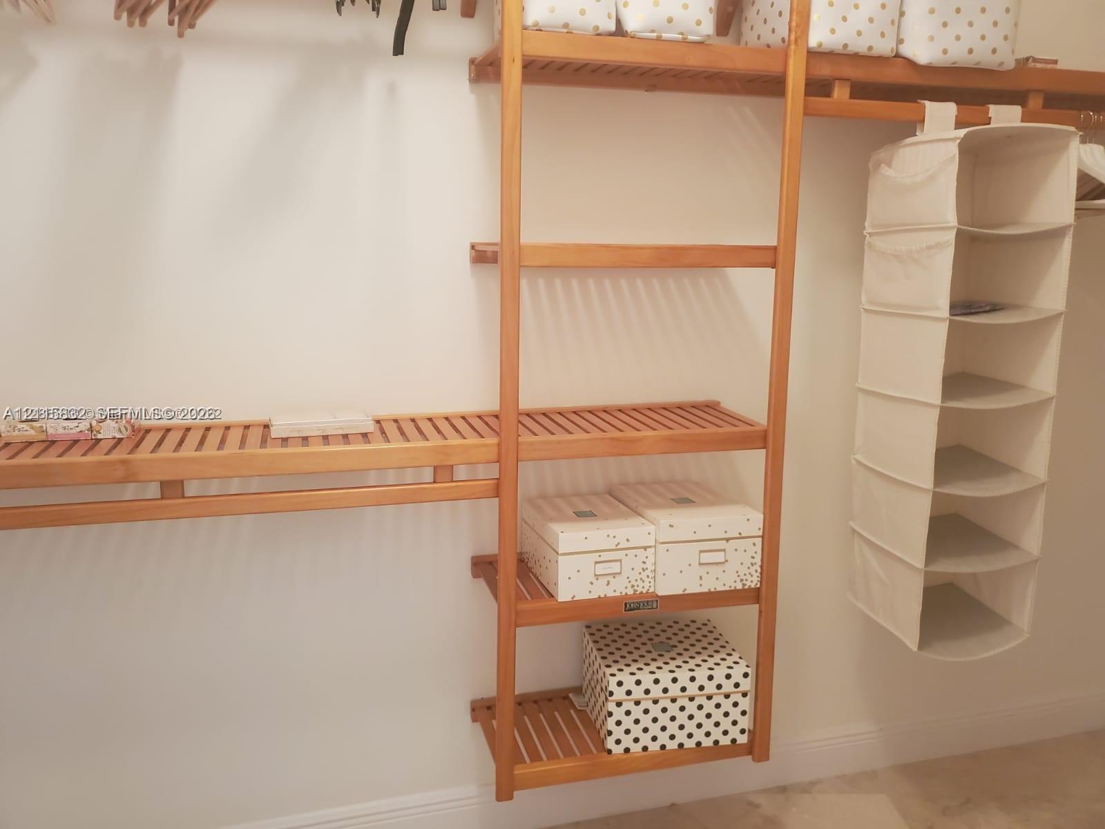 Custom-built wood shelving featuring multi-tiered vertical towers and slatted horizontal racks with integrated hanging rods