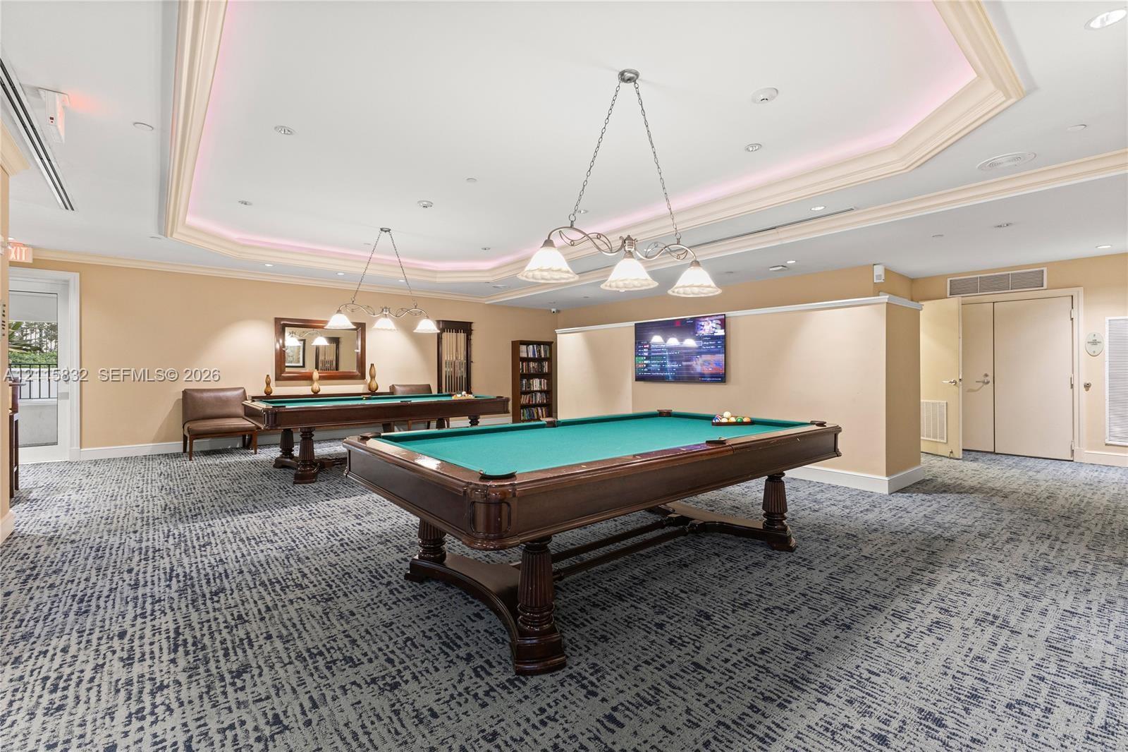 Tray ceiling with recessed ambient lighting, decorative multi-light chandeliers, and neutral wall tones