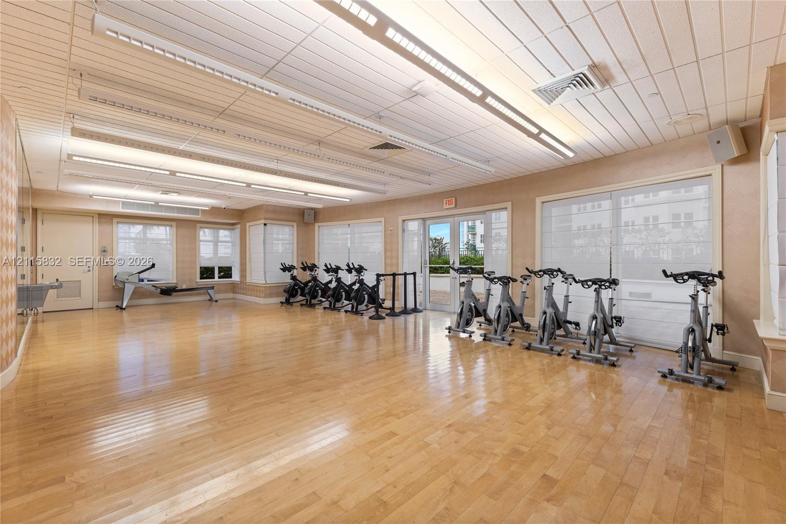 Fitness room featuring wood-finish flooring, linear recessed lighting, plank-style ceiling, and glass-paneled exterior doors