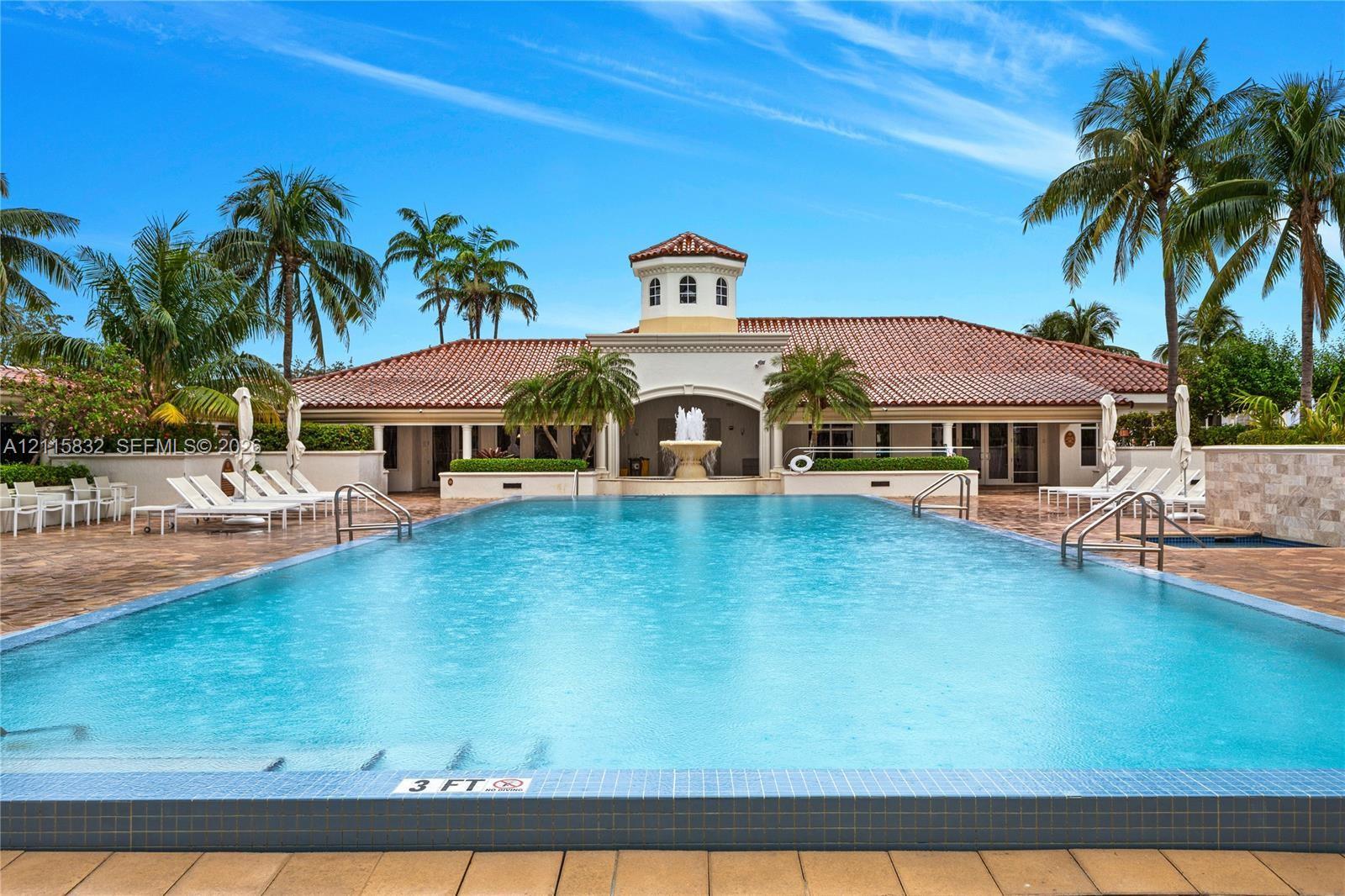 In-ground swimming pool with tile trim, decorative central fountain, tile-paved patio, and stucco exterior with a tiled roof