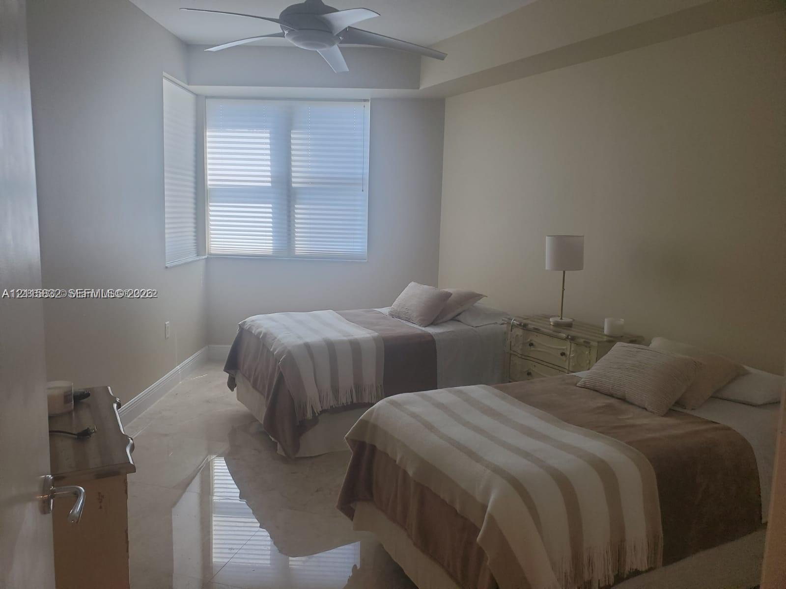Room featuring polished neutral-toned tile flooring, recessed window bay, and ceiling-mounted fan with integrated lighting