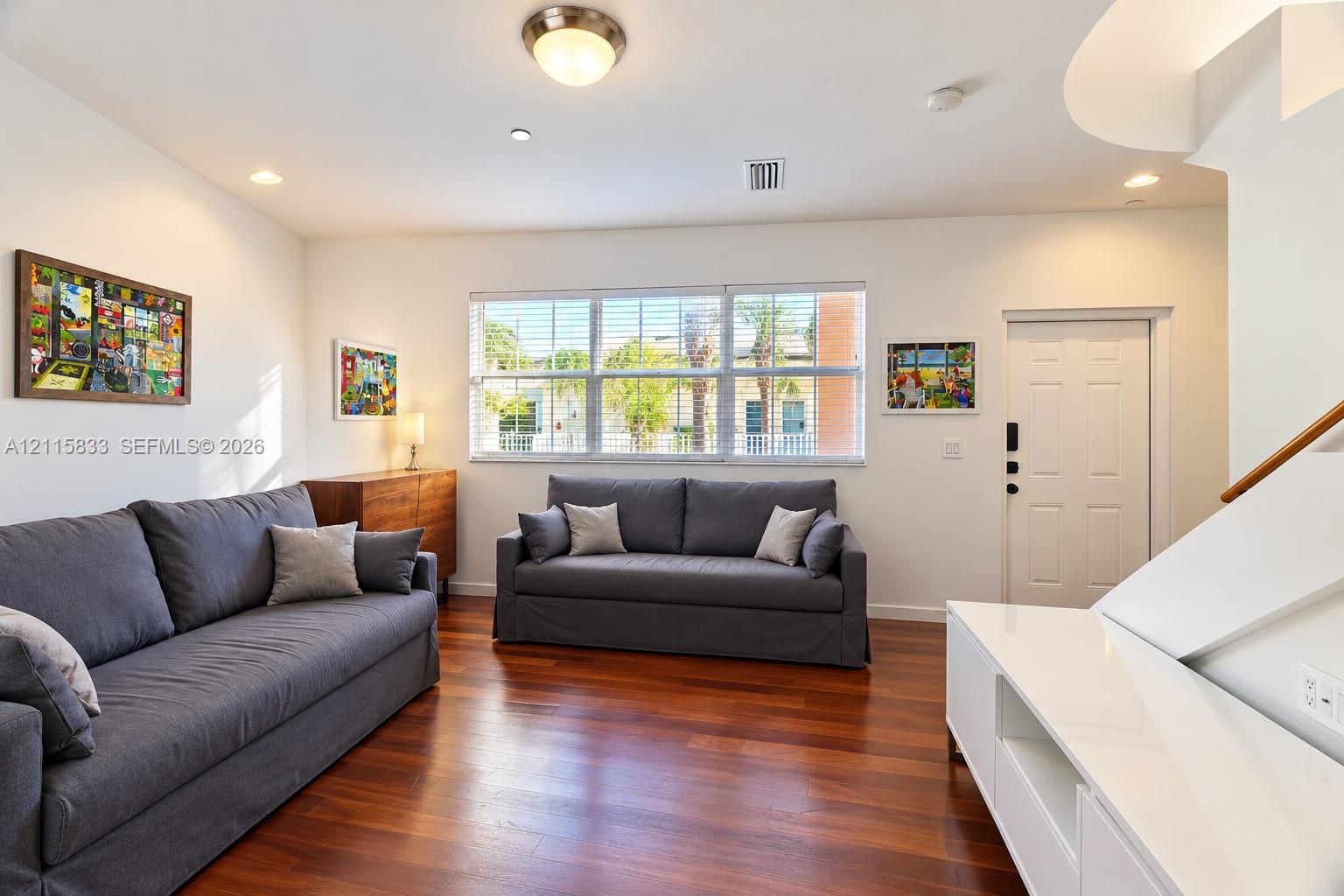 Living area featuring wood-finish flooring, recessed lighting, expansive multi-pane window, and white interior door