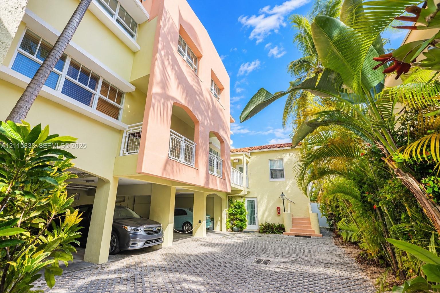 Stucco exterior featuring multi-level arched balconies, covered parking, and paved motor court