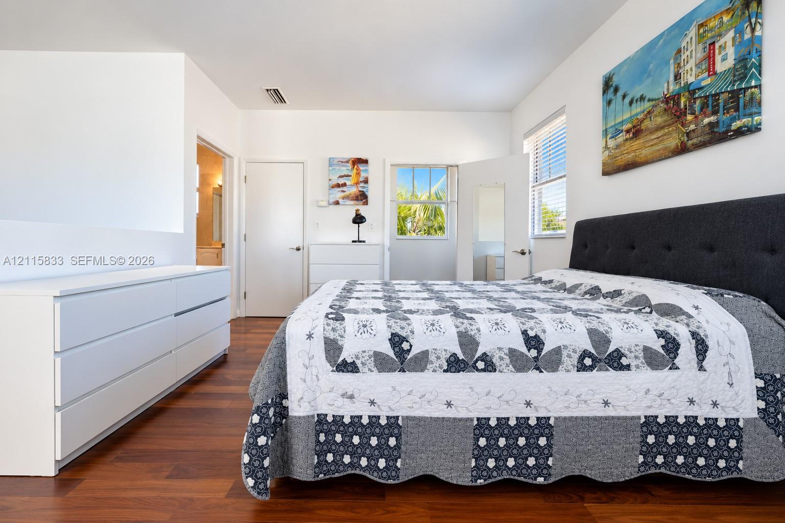 Wood-finish flooring, white walls, and multiple windows with horizontal blinds