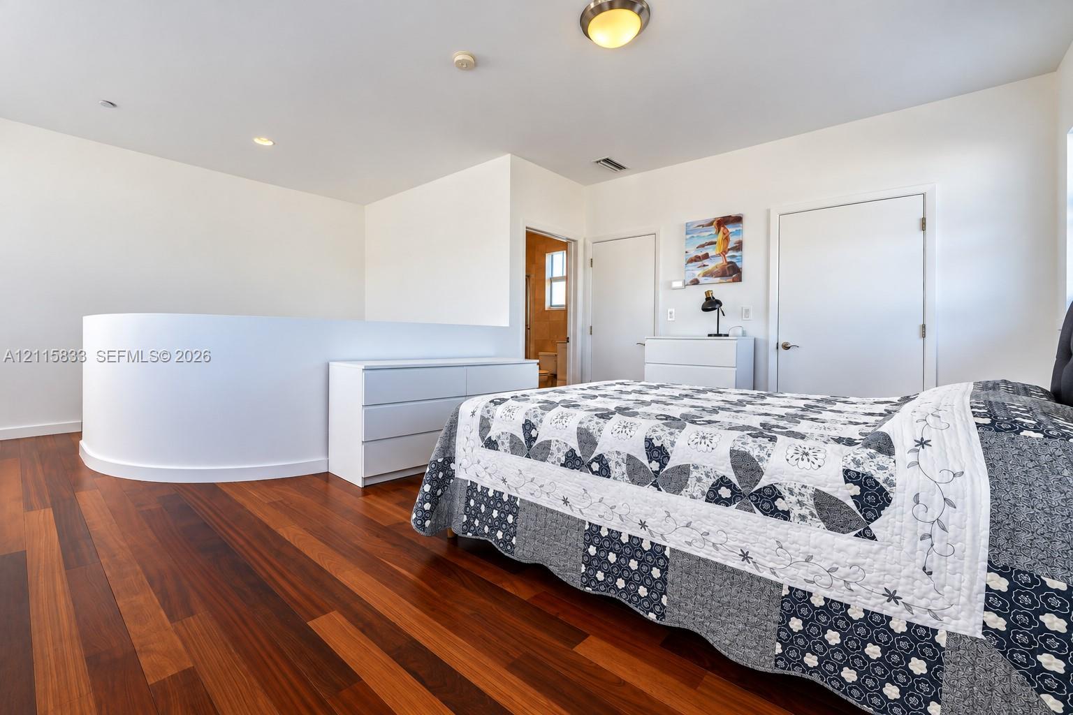 Wood-finish flooring, curved partition wall, and recessed ceiling lighting