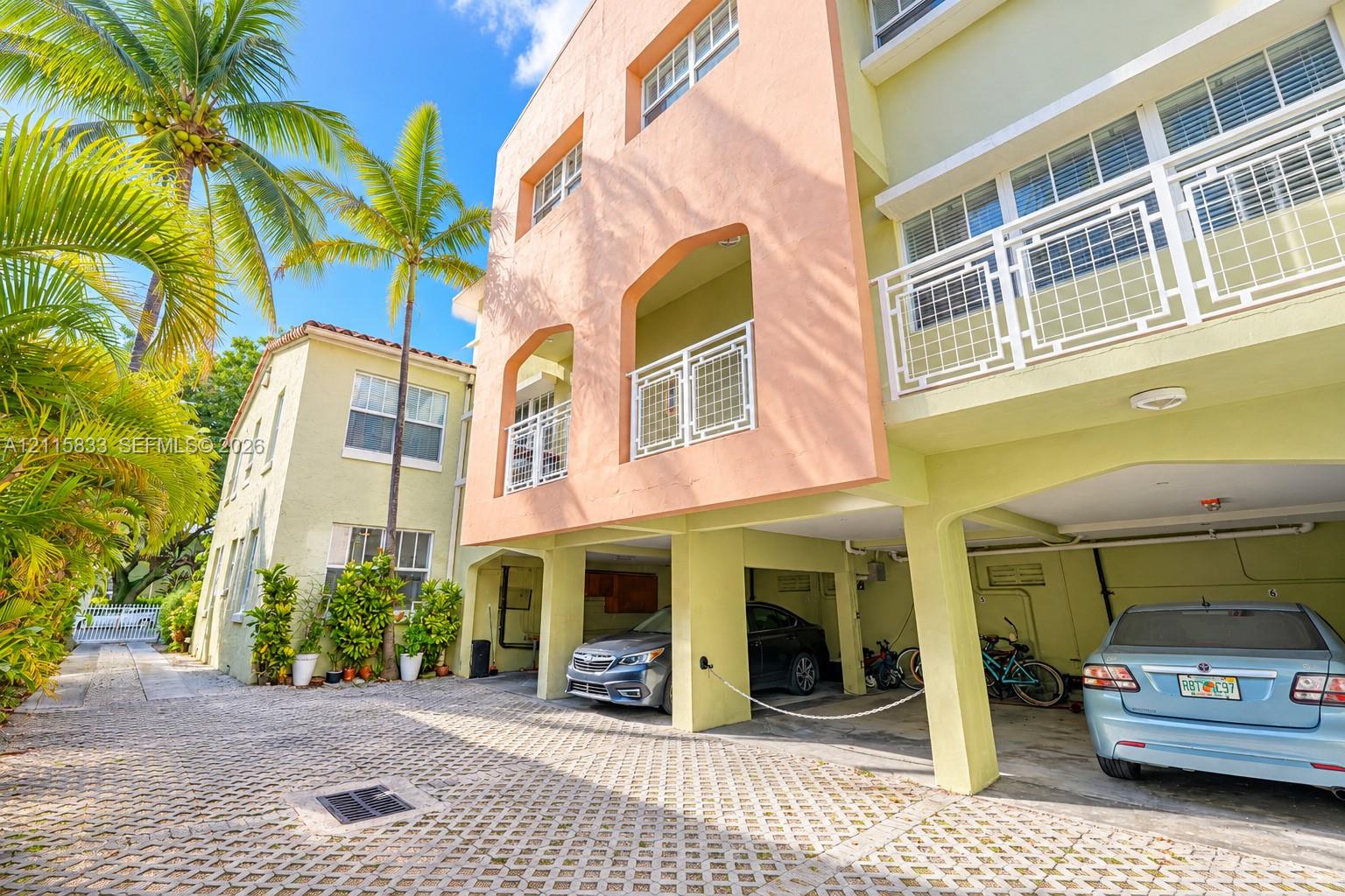 Multi-story exterior featuring a pastel stucco facade, covered ground-level parking, and decorative geometric balcony railings