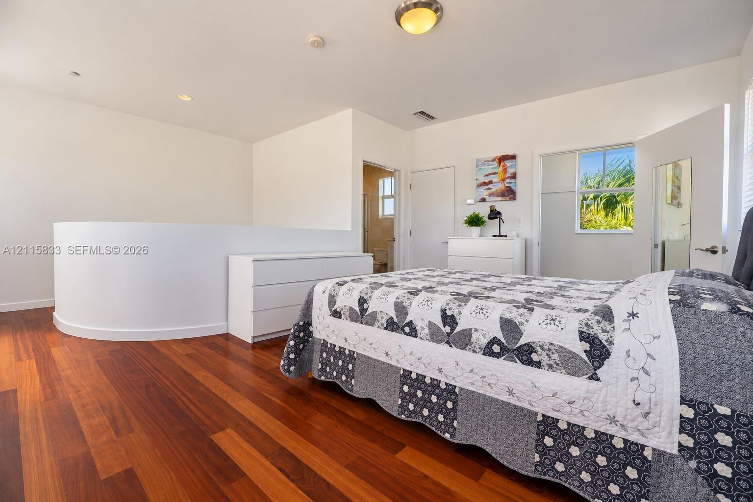 Wood-finish flooring, curved architectural wall detail, and flush-mount ceiling lighting