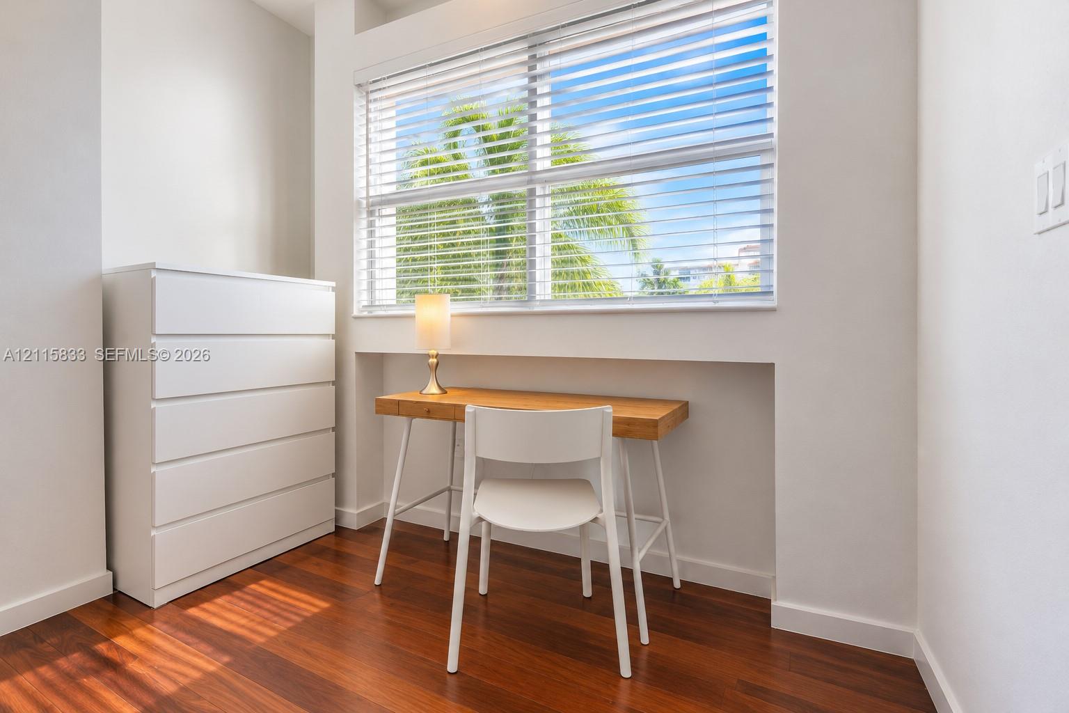 Interior space featuring wood-finish flooring, a recessed window alcove, and horizontal window blinds