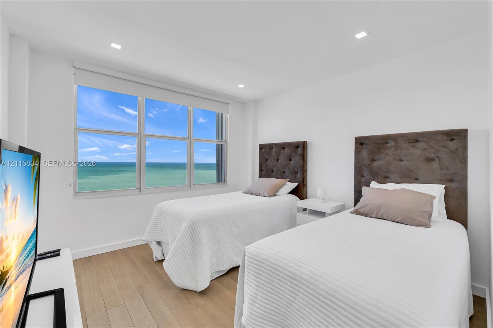 Large windows with ocean scenery, wood-finish flooring, and recessed ceiling lighting