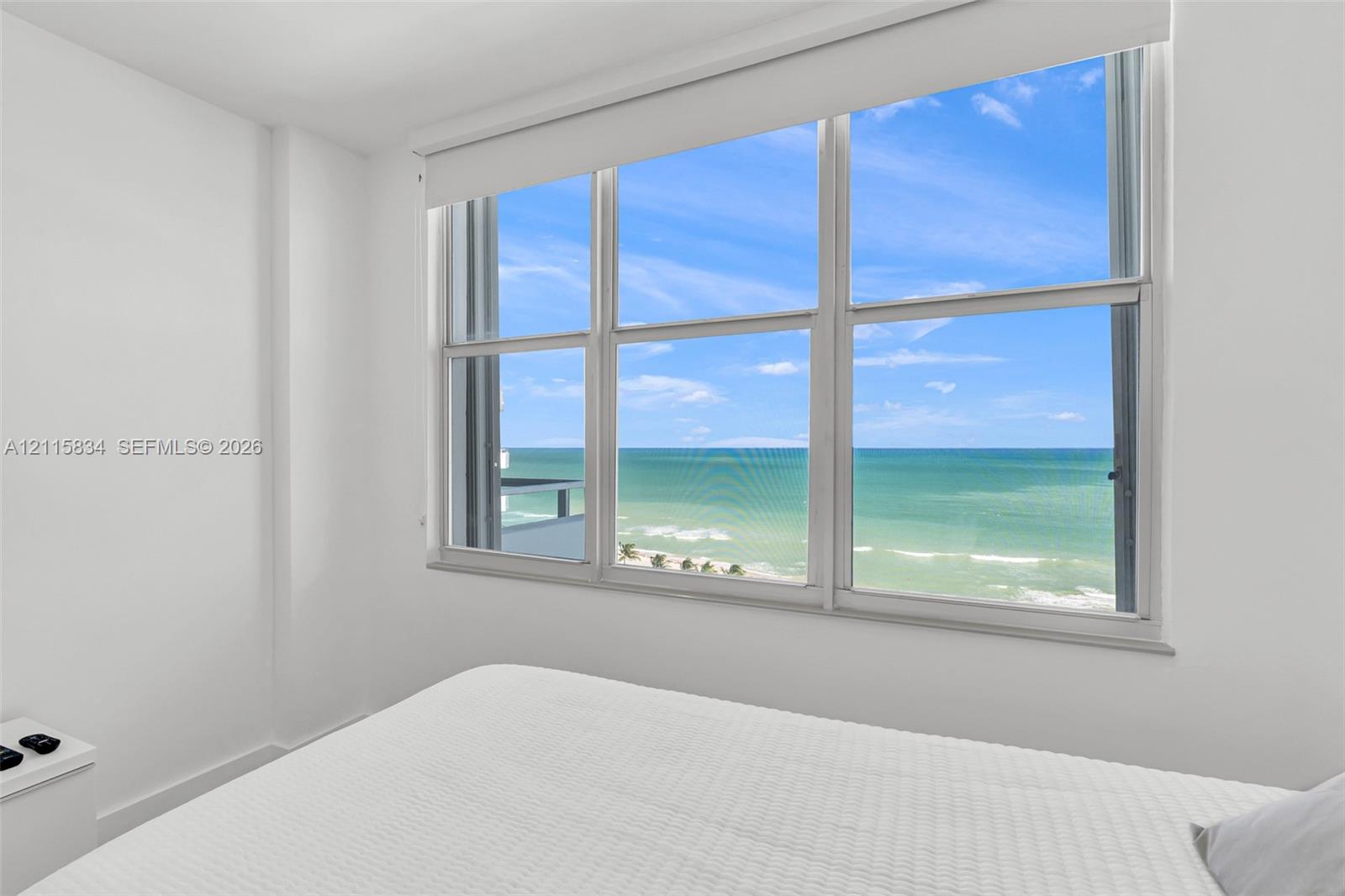 Large multi-pane window with a retractable shade, providing expansive ocean and coastline scenery