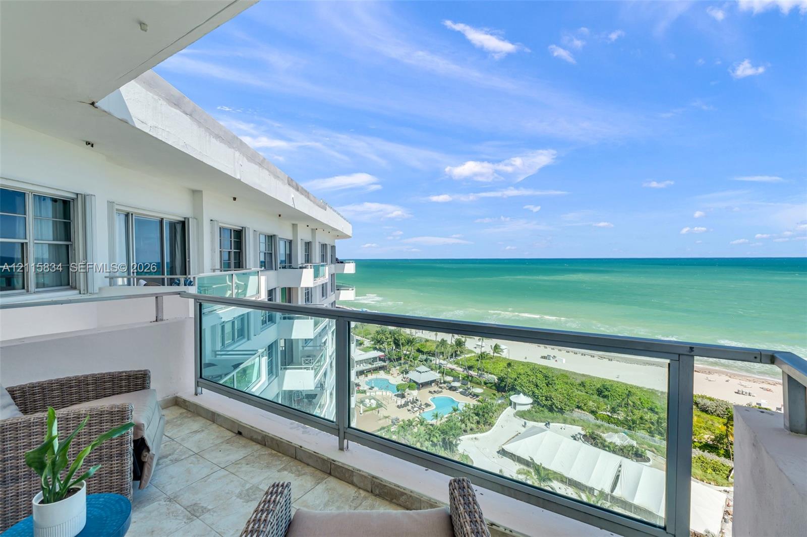 Private balcony featuring tile flooring and a glass-paneled railing overlooking the ocean and coastline