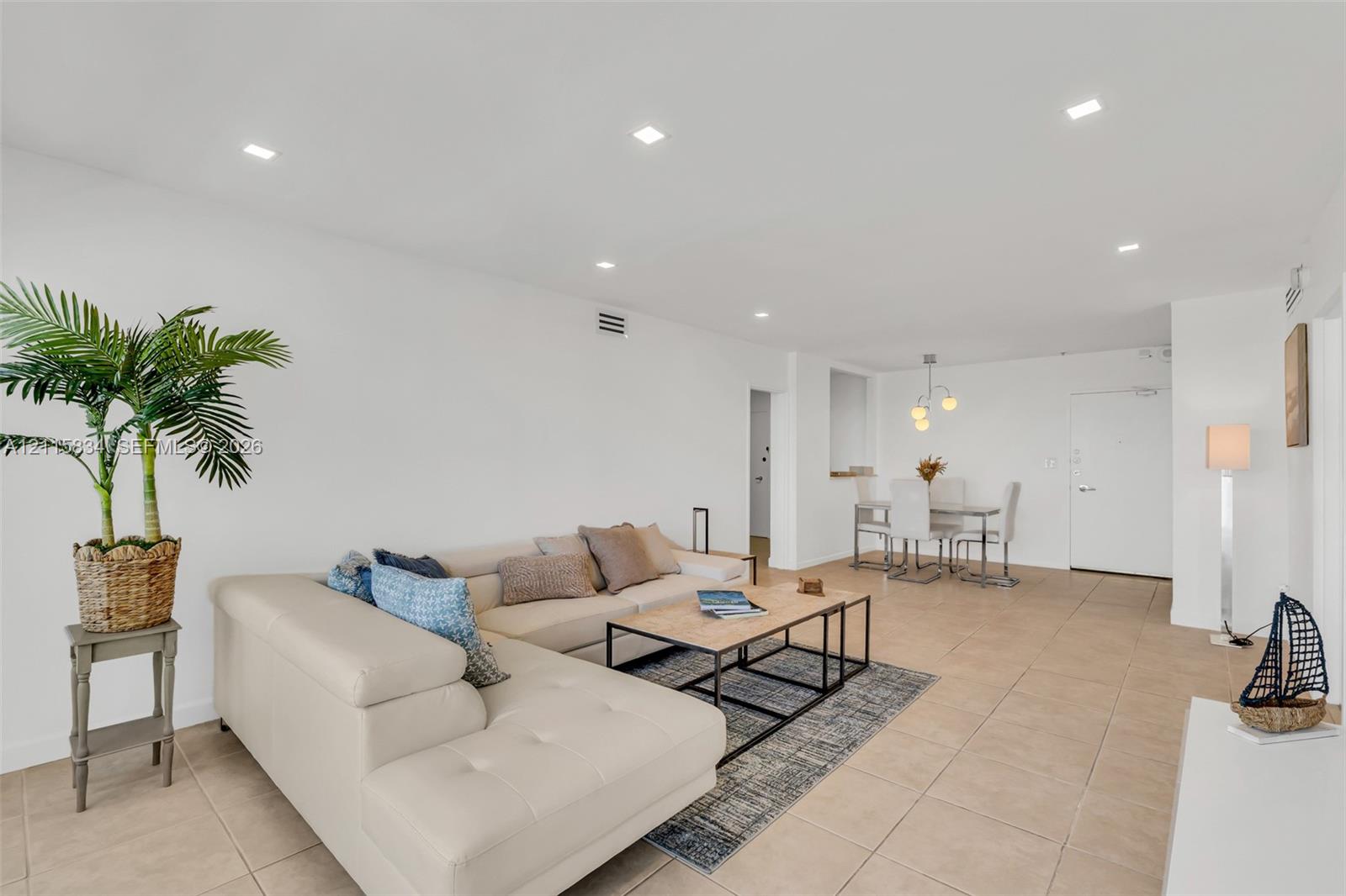 Open-concept interior featuring neutral tile flooring, recessed ceiling lighting, and a modern multi-globe chandelier
