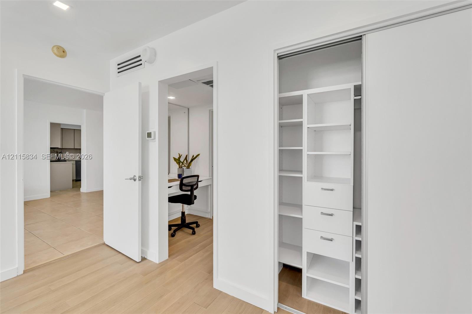 Custom-built walk-in closet featuring integrated shelving and drawer organizers, light-toned wood-finish flooring, and recessed ceiling lighting
