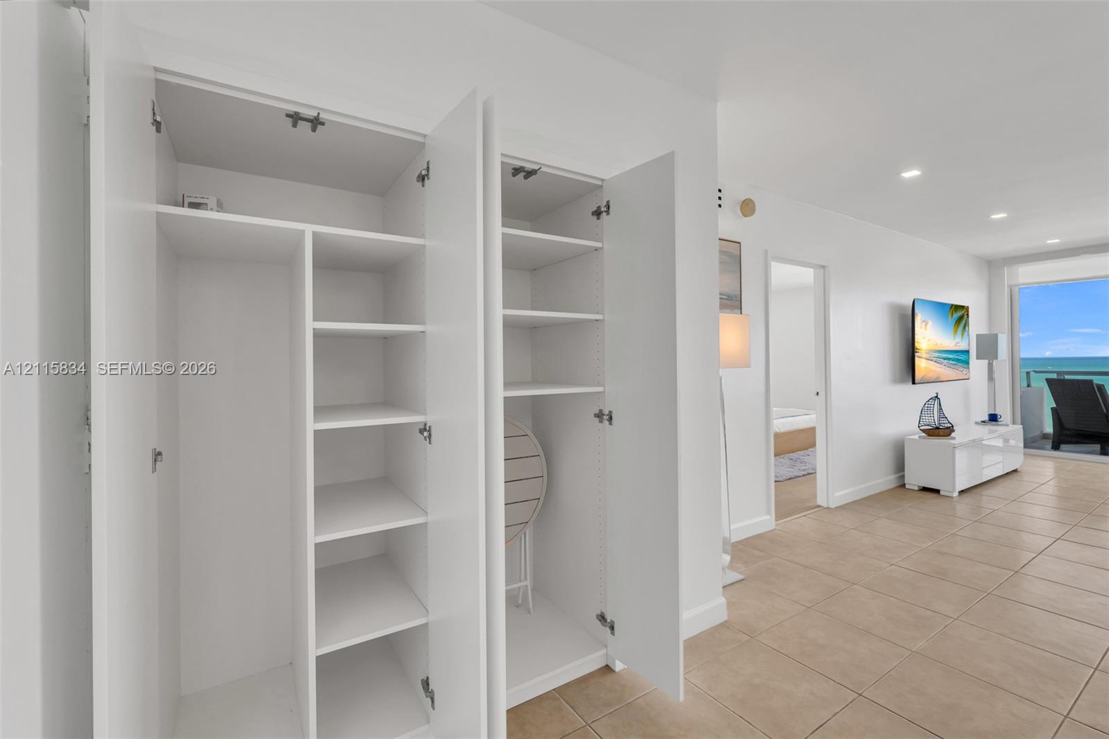 Built-in cabinetry featuring white laminate doors and adjustable shelving, complemented by tile flooring and recessed lighting