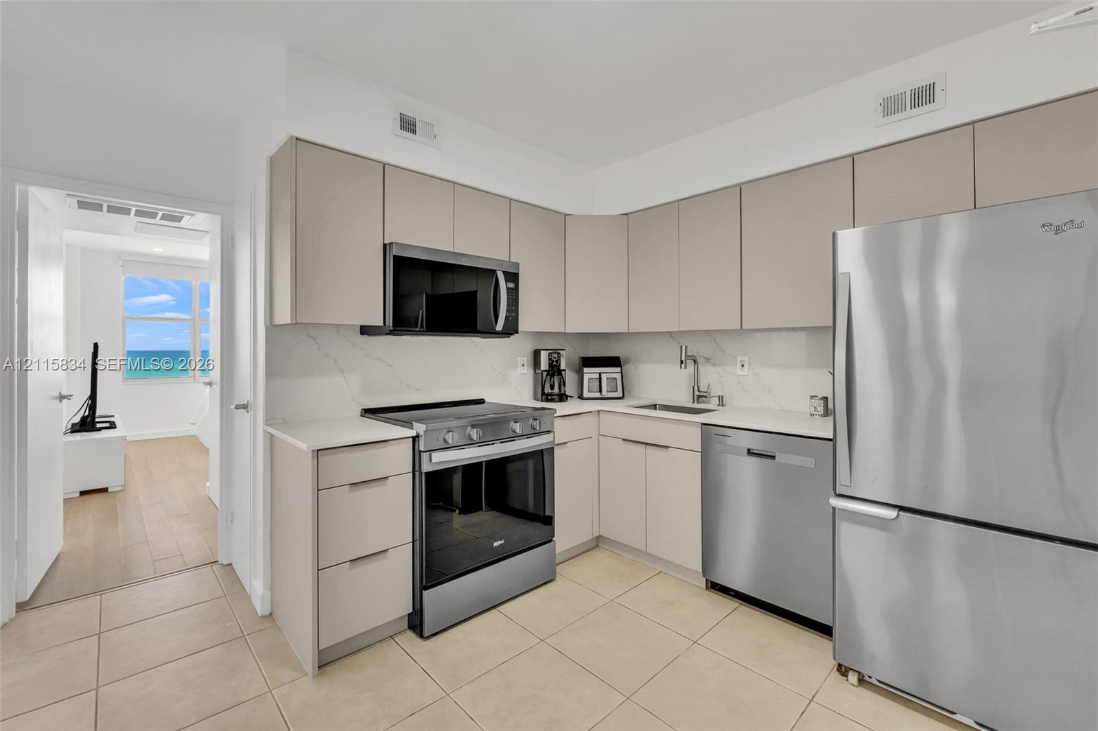 Kitchen featuring flat-panel cabinetry, quartz countertops, veined stone-style backsplash, and stainless steel appliances