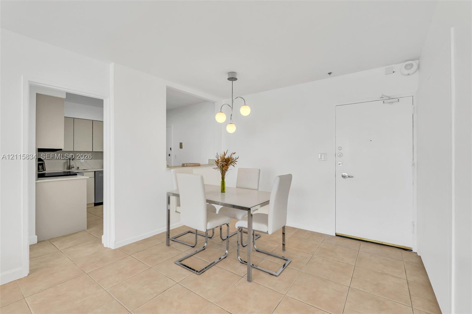 Neutral-toned tile flooring, three-globe pendant lighting fixture, and solid-panel door with integrated security hardware