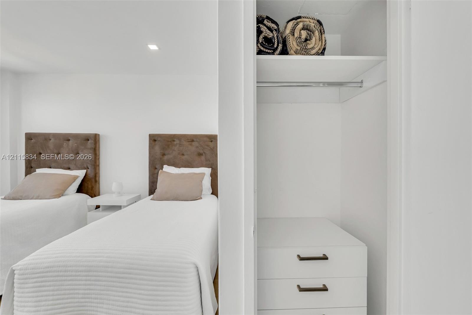 Built-in closet featuring white cabinetry, two drawers with matte black hardware, an upper storage shelf, and a metal hanging rod