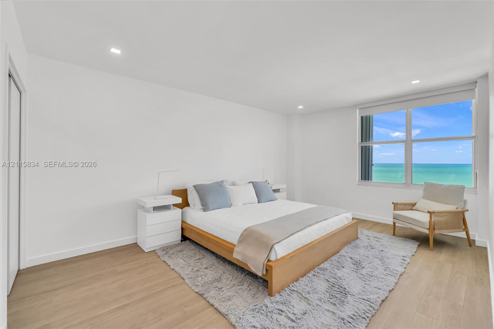 Neutral-toned interior featuring wood-finish flooring, recessed lighting, and expansive windows with ocean scenery
