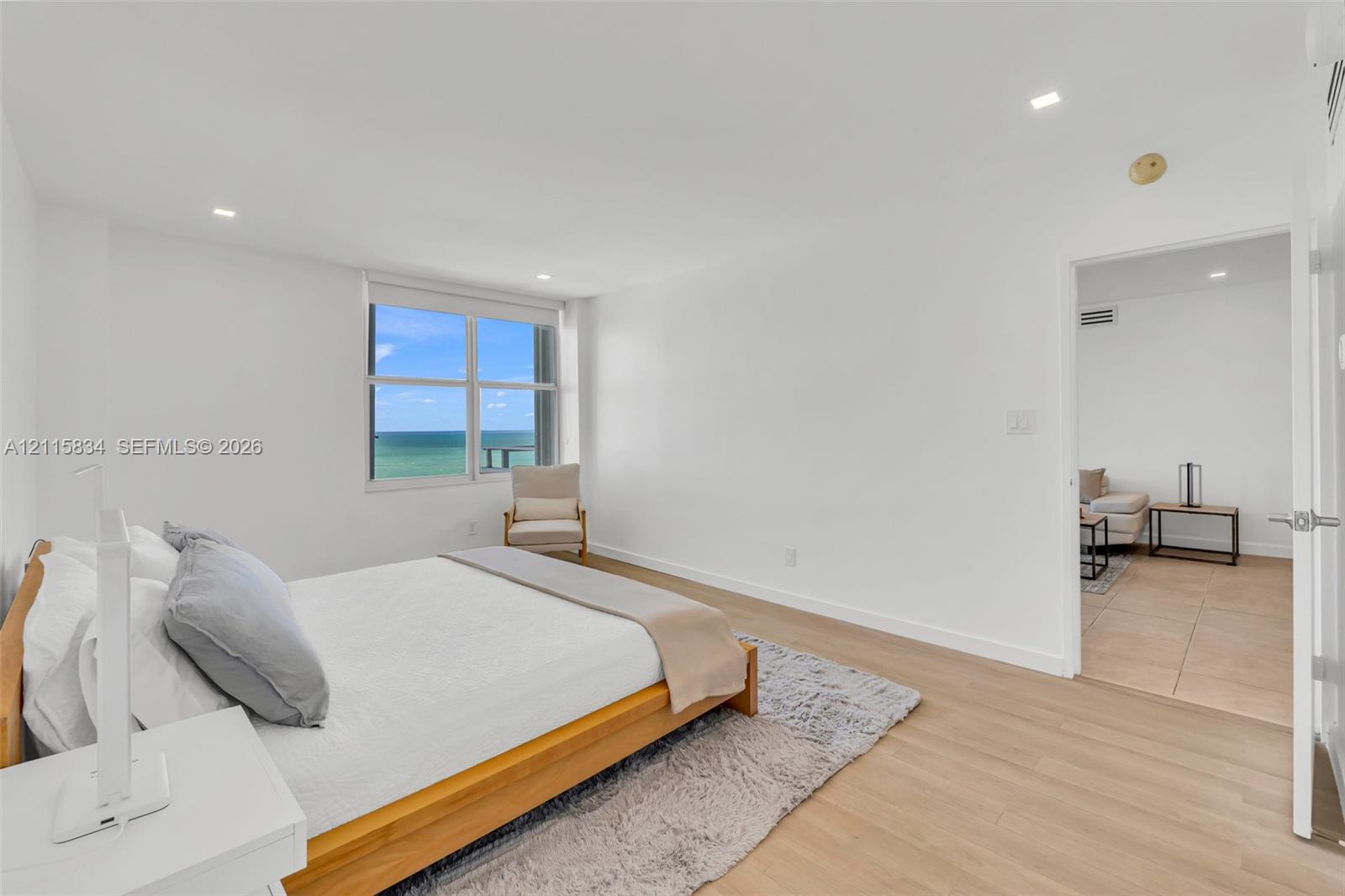 Spacious room featuring wood-finish flooring, recessed lighting, and a large window showcasing a prominent ocean backdrop