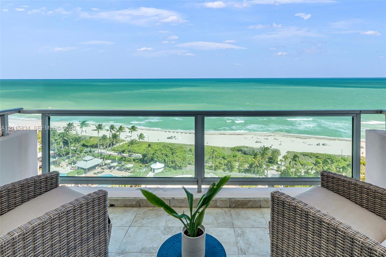 Private balcony with a metal and glass railing, stone flooring, and expansive coastal water backdrop