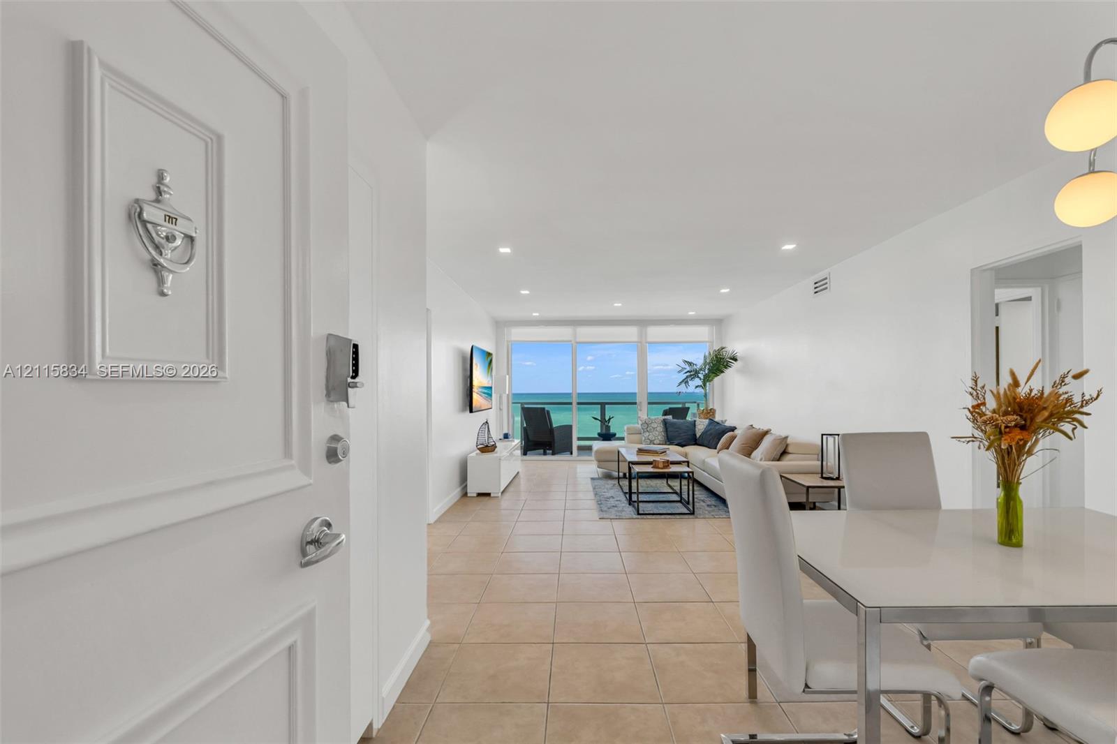 Entryway featuring a decorative metal door knocker, large-format tile flooring, recessed ceiling lighting, a modern multi-pendant light fixture, and floor-to-ceiling glass paneling