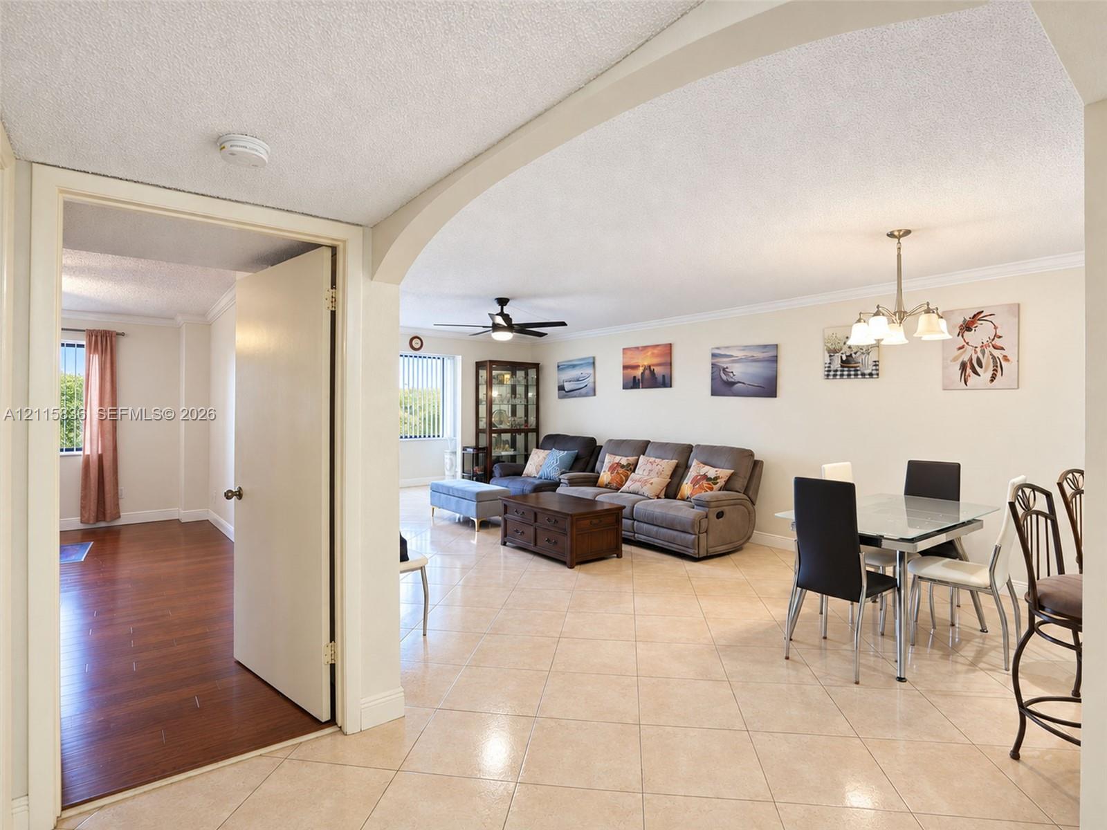 Open-concept interior featuring arched architectural detailing, polished ceramic tile flooring, wood-finish flooring, and a multi-arm chandelier