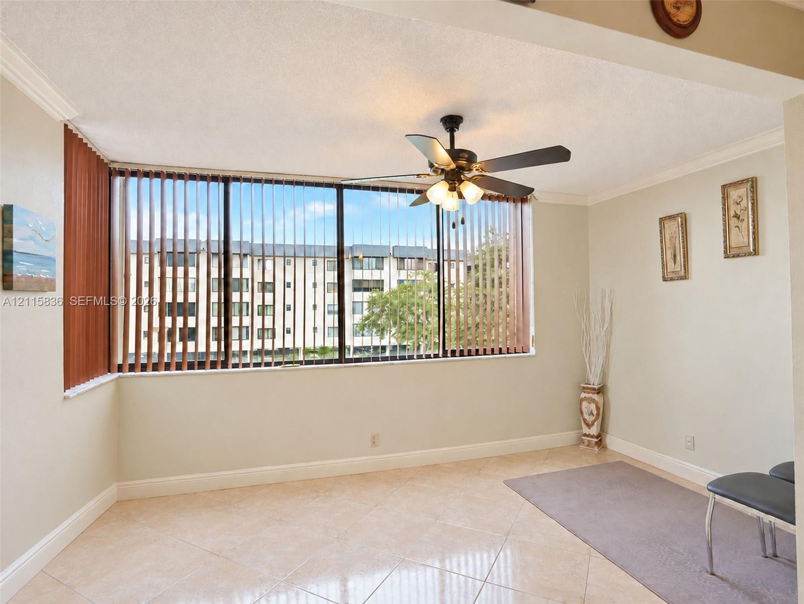Floor-to-ceiling windows with vertical blinds, tile flooring, and a ceiling fan with integrated lighting