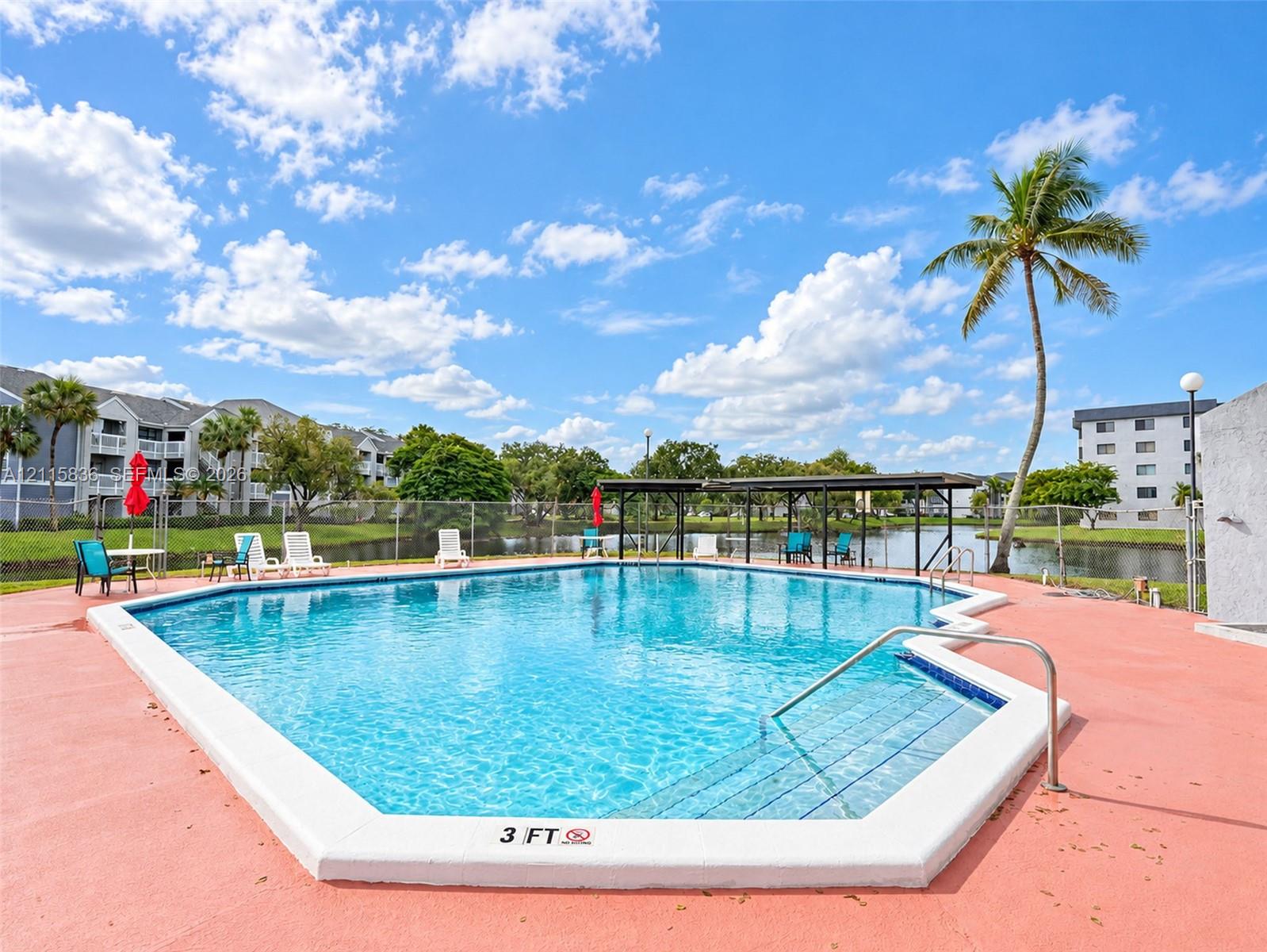 In-ground swimming pool featuring a concrete deck, tiled entry steps, and metal handrails