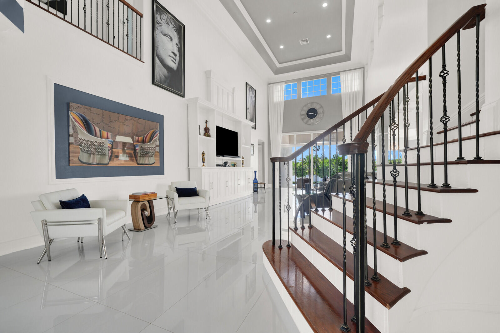 Grand entryway featuring a sweeping staircase with dark wood treads and decorative wrought iron balusters