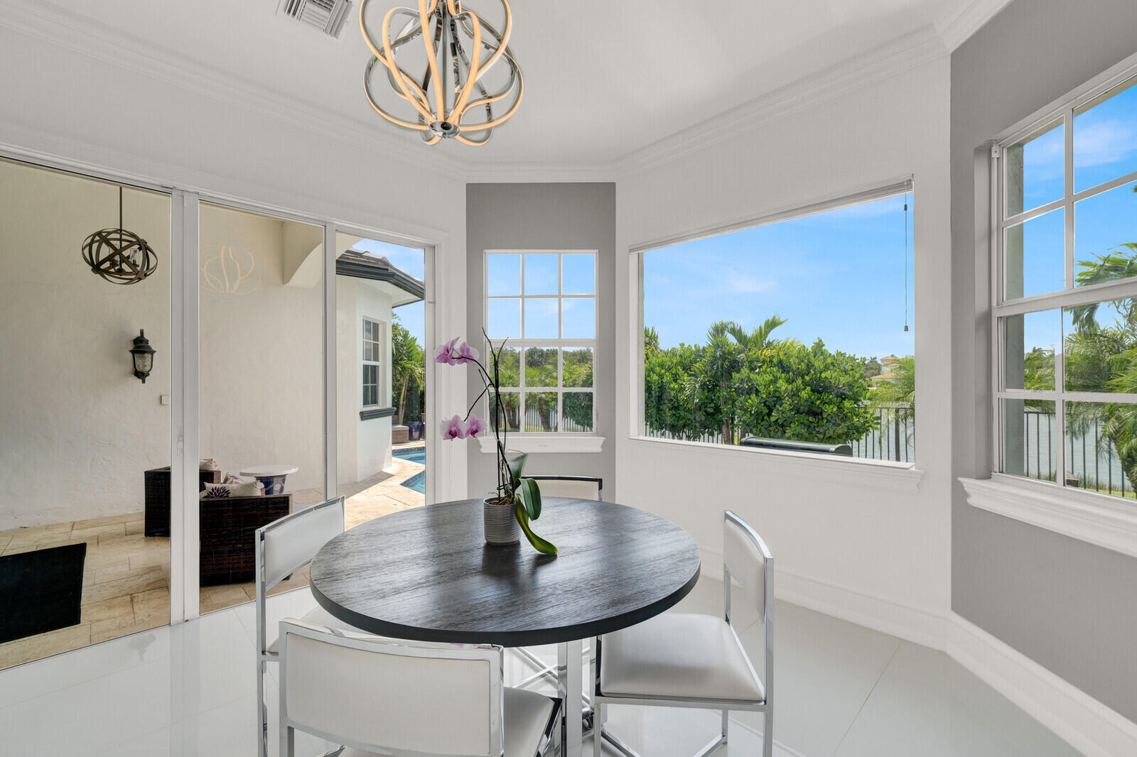Bright interior space featuring a contemporary chandelier, large windows, and sliding glass doors opening to an exterior patio with a pool