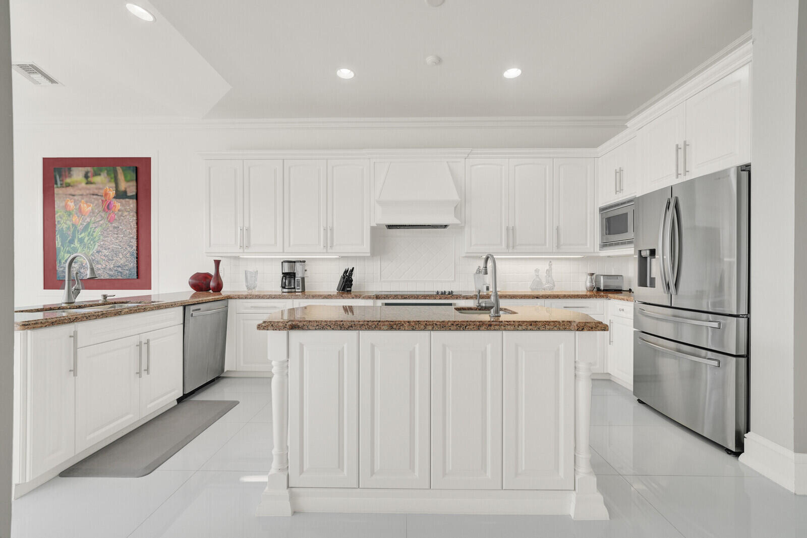 Bright kitchen featuring white cabinetry, a central island, stainless steel appliances, and light-toned countertops