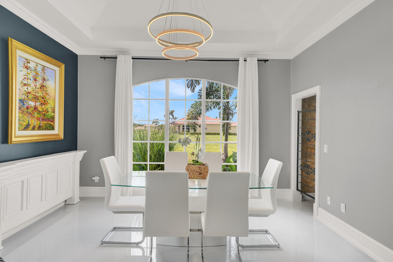 Dining area featuring an arched window, tray ceiling, and light-tone flooring
