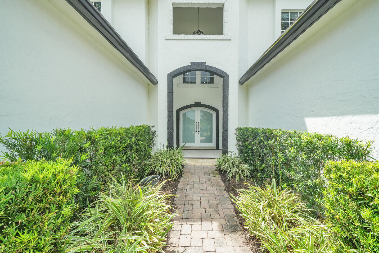 Brick paver walkway framed by mature shrubs and vibrant landscaping
