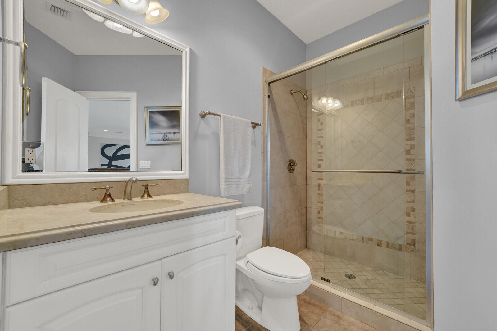 Bathroom featuring a vanity with a light-toned countertop, an undermount sink, and a framed mirror