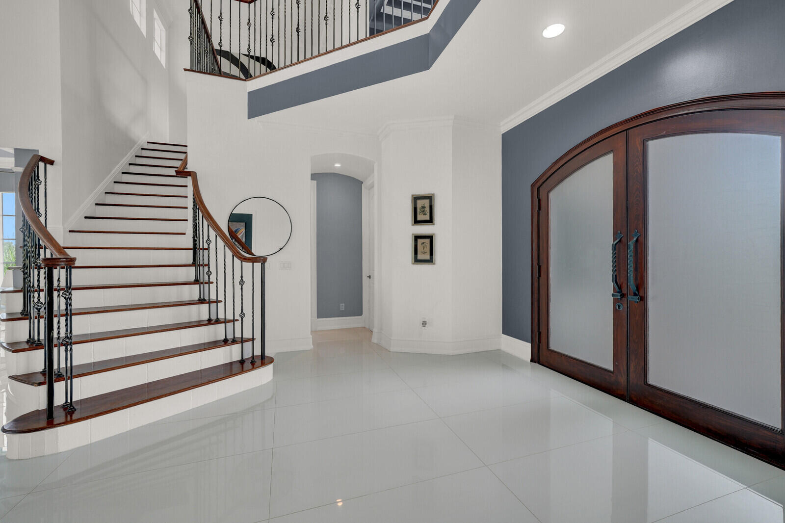 Grand foyer featuring a curved staircase with wood treads and wrought iron balusters