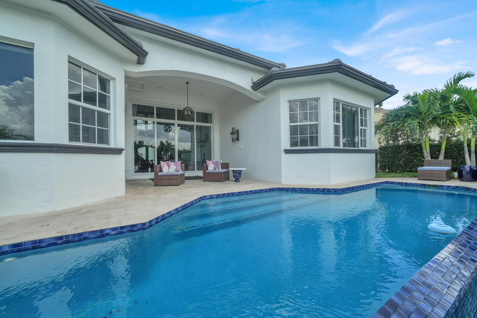 Swimming pool with blue tile edging, surrounded by a light-toned patio