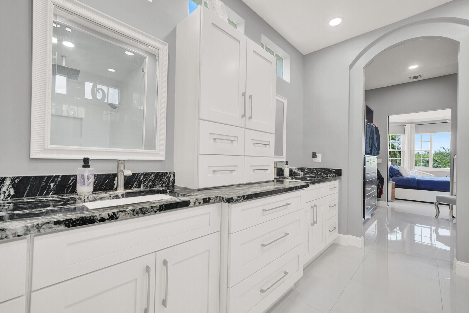 Double vanity with black and white stone countertops, white cabinetry, and brushed nickel hardware