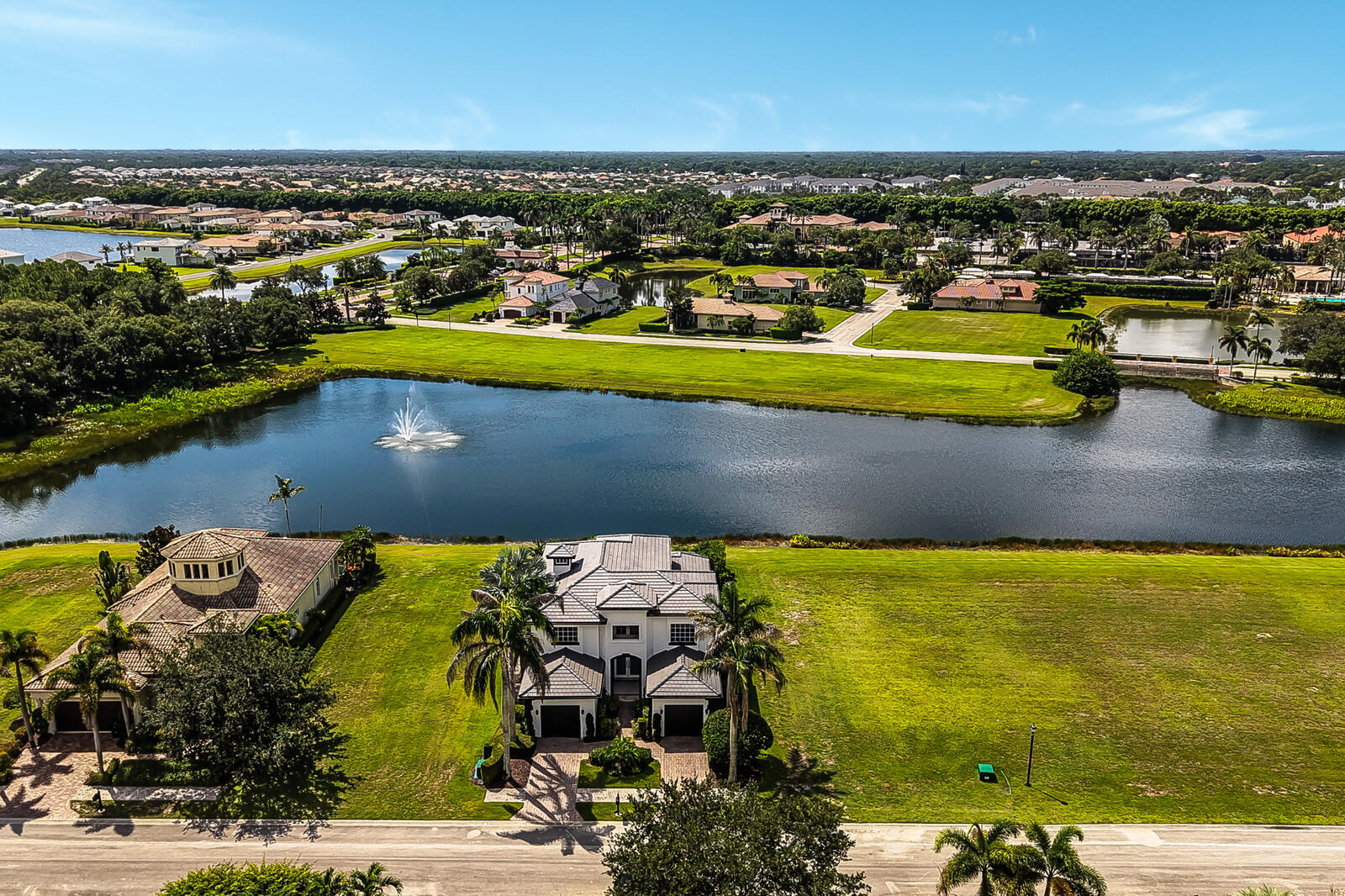 Stately residence featuring a multi-story design, a dark tile roof, and multiple garage bays