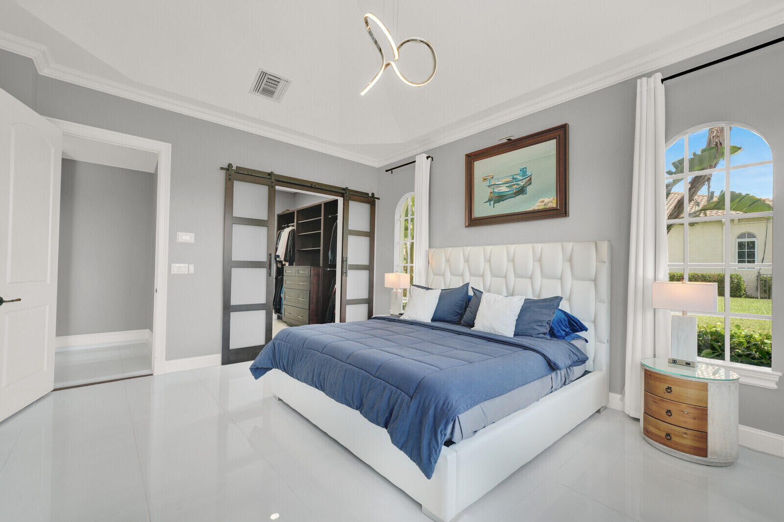 Bright sleeping area featuring high-gloss flooring, crown molding, and two arched windows