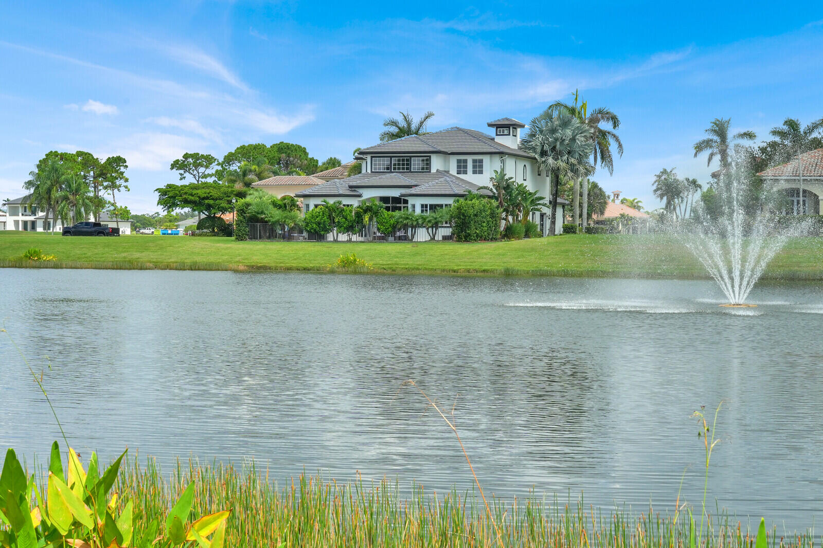 Waterfront property featuring a two-story residence with a turret, dark roof tiles, and manicured landscaping