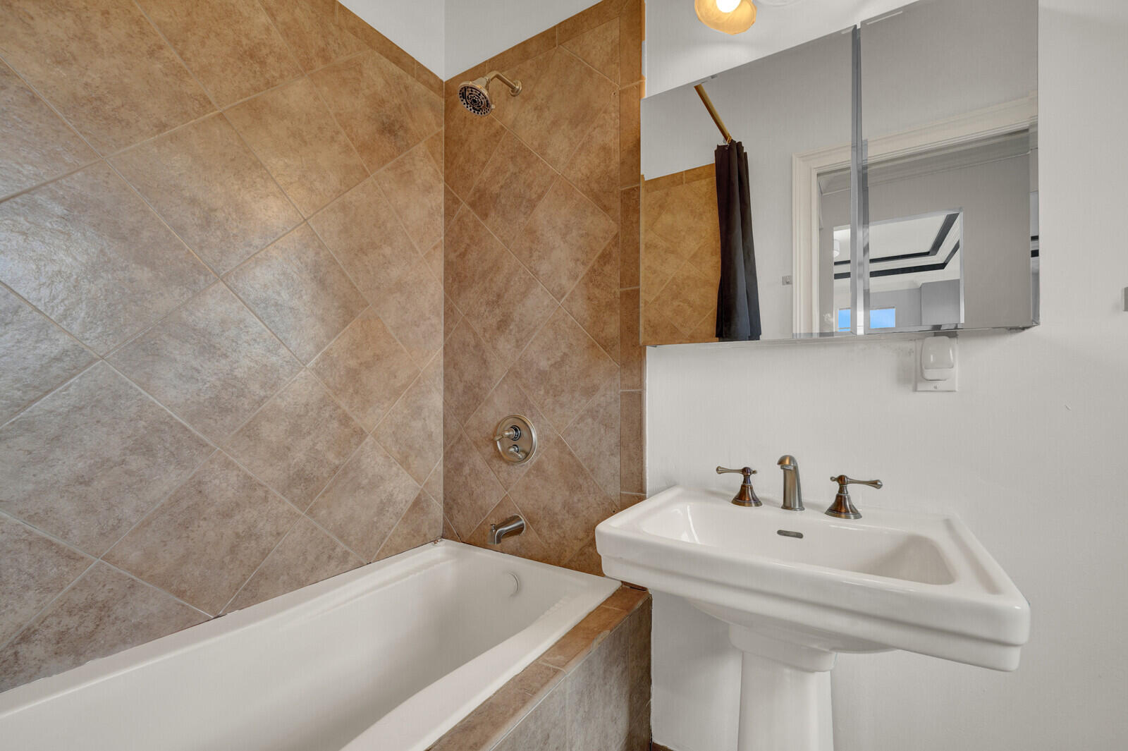 Bathroom featuring a pedestal sink, brushed bronze fixtures, and a medicine cabinet with integrated lighting