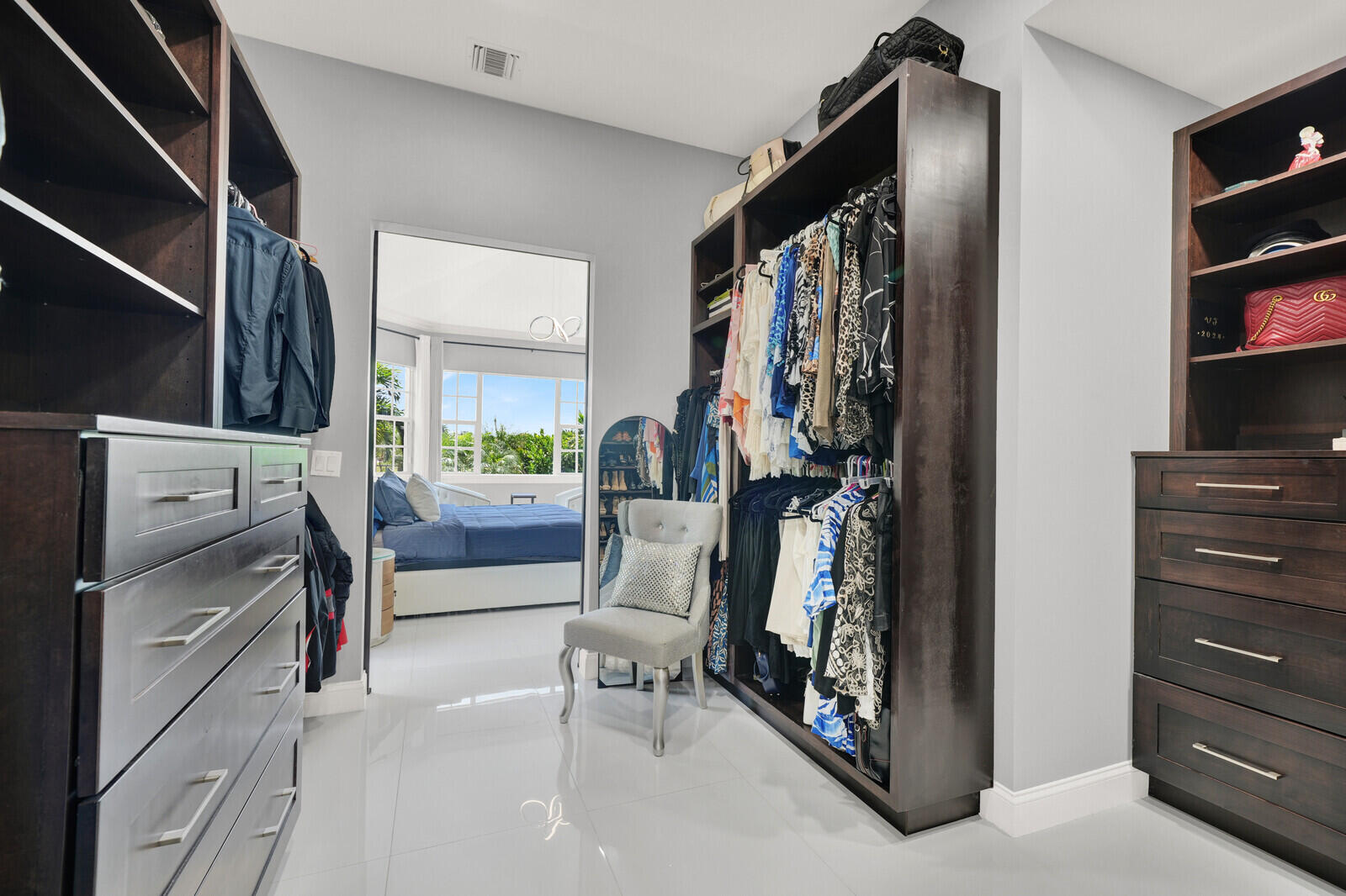 Custom closet system featuring dark wood-finish cabinetry, ample shelving, and integrated drawers with contemporary pull hardware