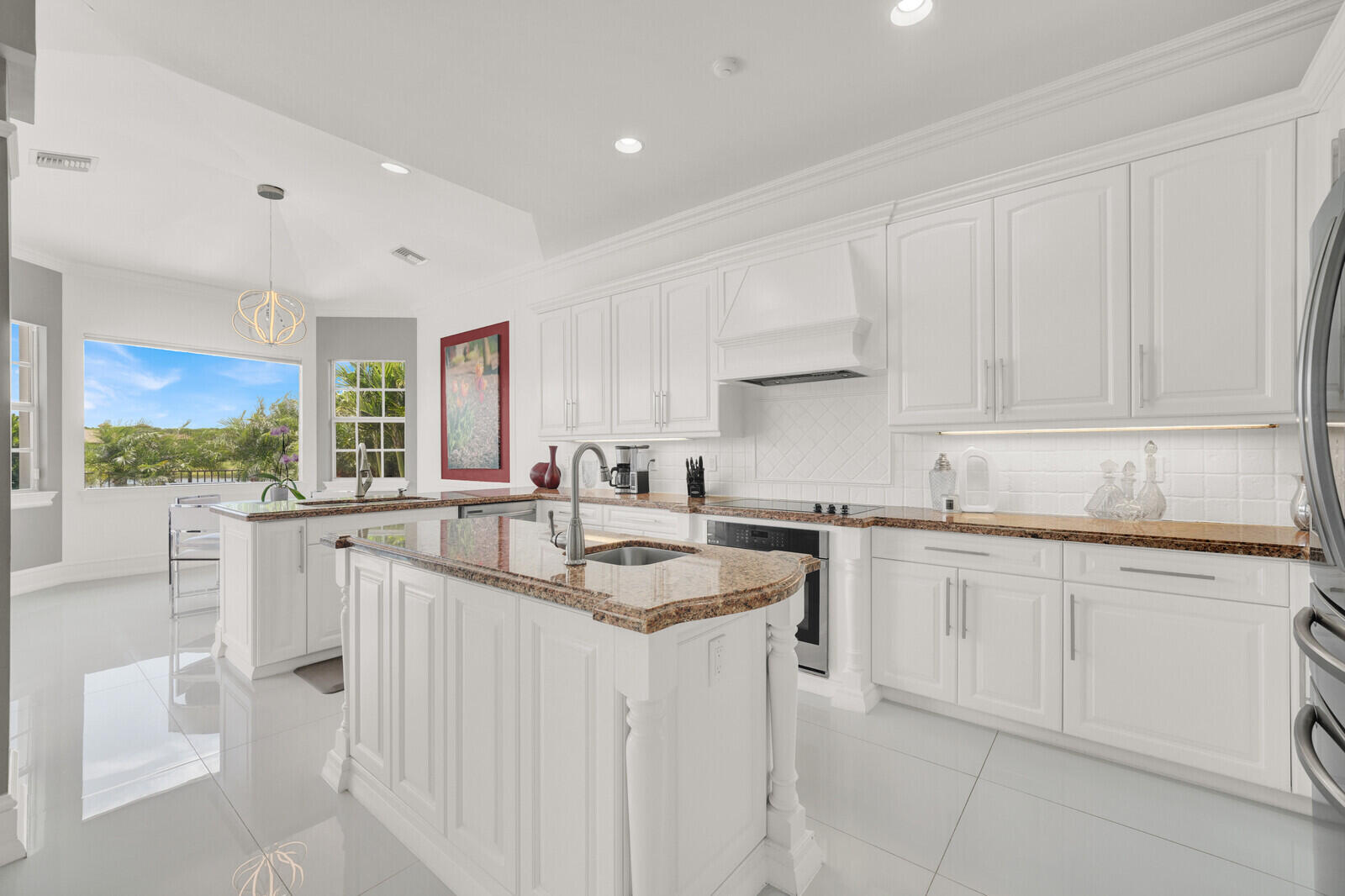 Bright kitchen featuring white cabinetry, polished tile flooring, and a central island with a granite-style countertop