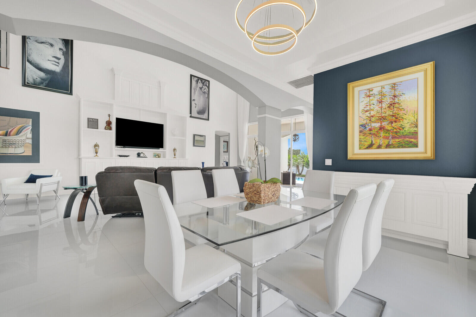 Open-concept living space featuring high ceilings, white tile flooring, and a built-in media center with shelving