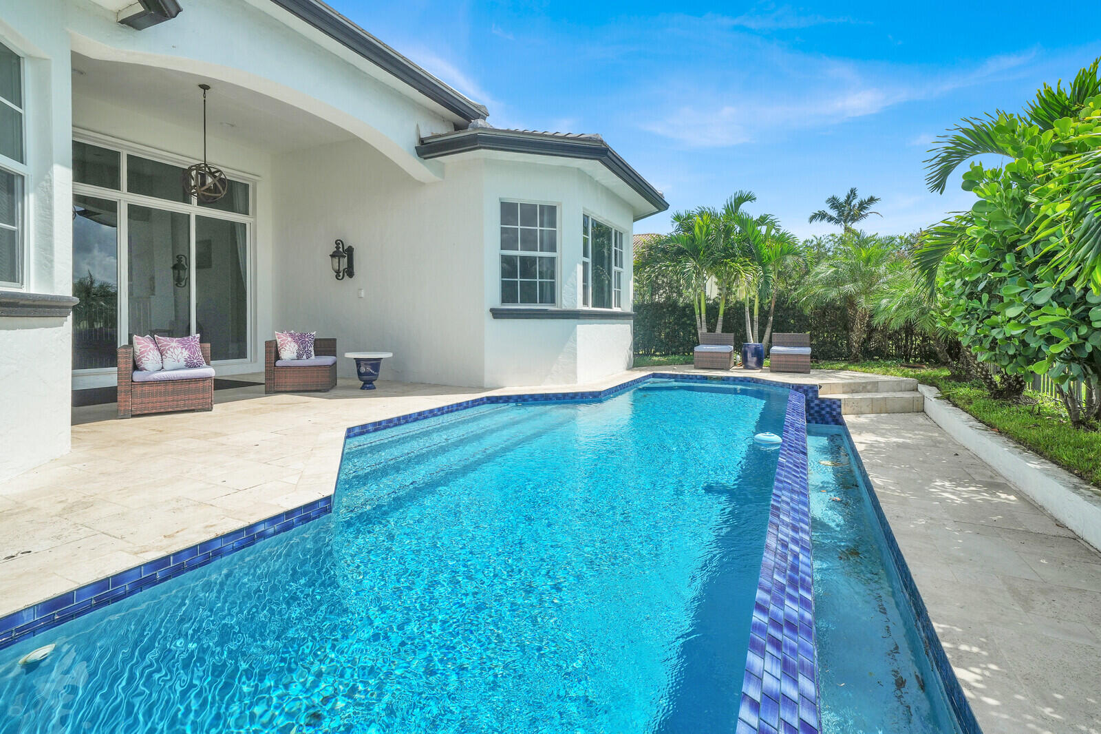 Contemporary outdoor living area featuring a rectangular swimming pool with blue tile accents and an integrated spa