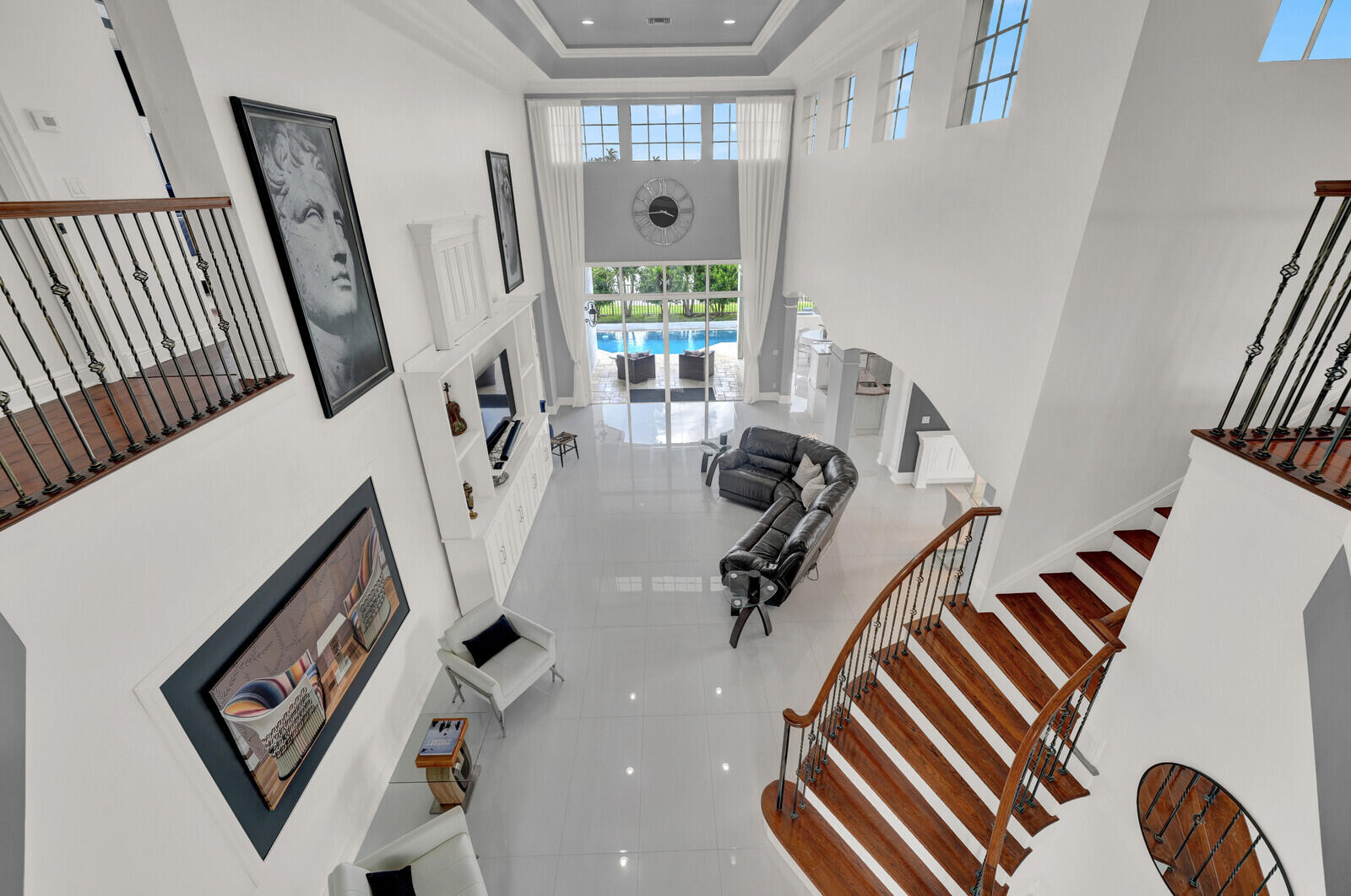 Grand entry hall featuring a high ceiling, polished tile flooring, and a curved wood staircase with wrought iron balusters