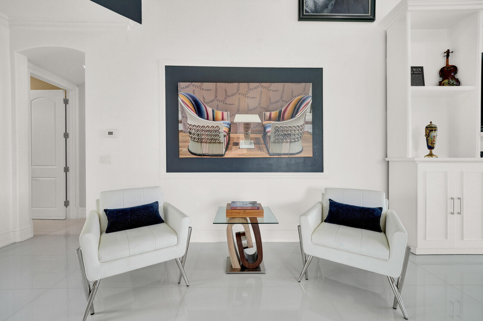White wall with built-in shelving, white baseboards, and a white door with an arched frame